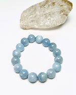 Load image into Gallery viewer, Blue beaded bracelet on a white background with a crystal rock.