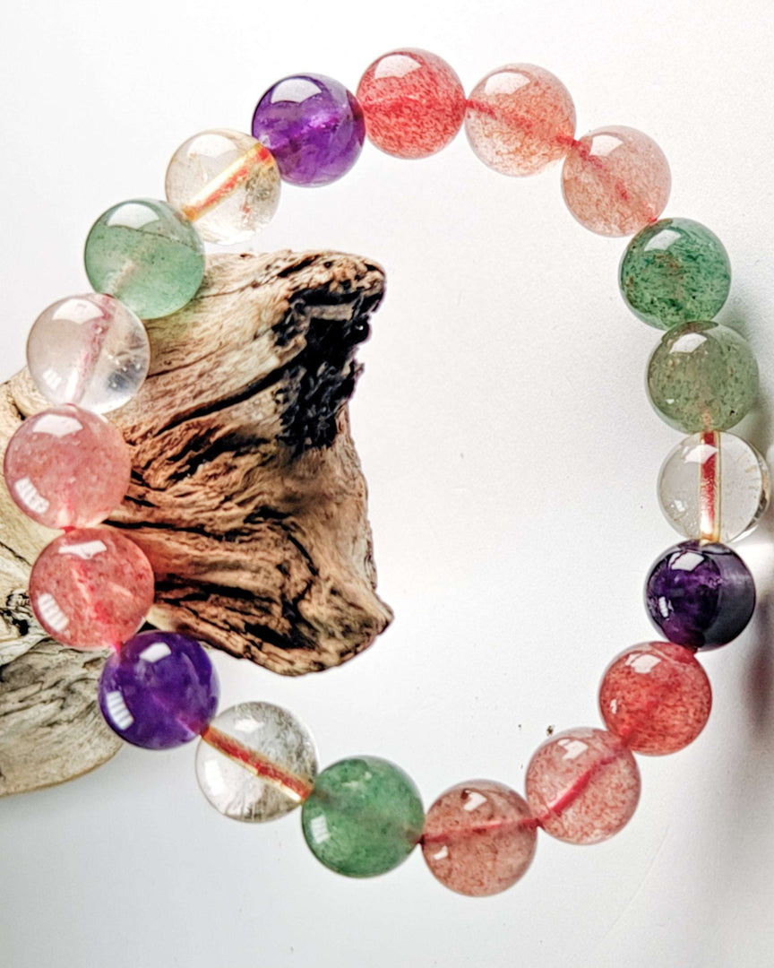 Multicolored beaded bracelet on a white background with a piece of driftwood.