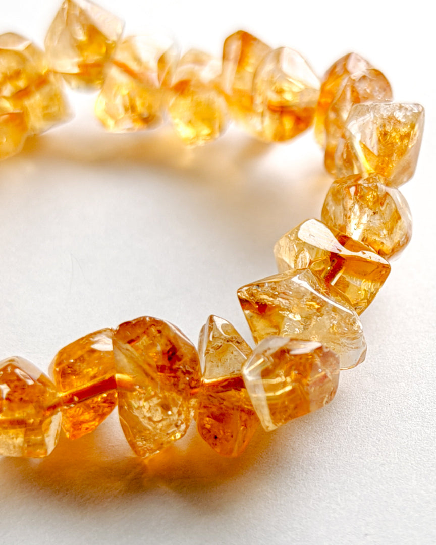 Close-up of a bracelet with amber-colored beads on a white background