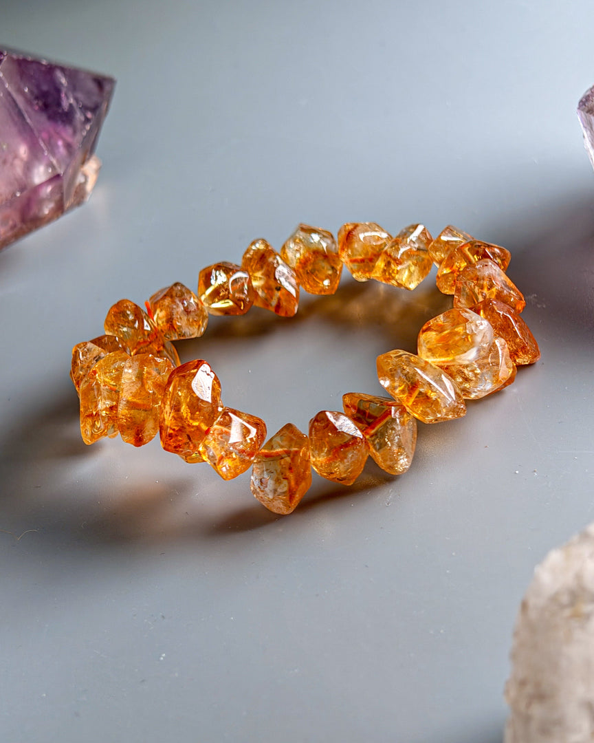Orange crystal bracelet on a light gray surface with crystals around