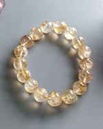Load image into Gallery viewer, Beaded bracelet with yellow gemstones on a gray background
