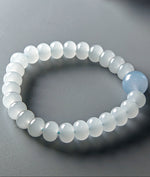 Load image into Gallery viewer, Beaded bracelet with a single blue bead on a gray background
