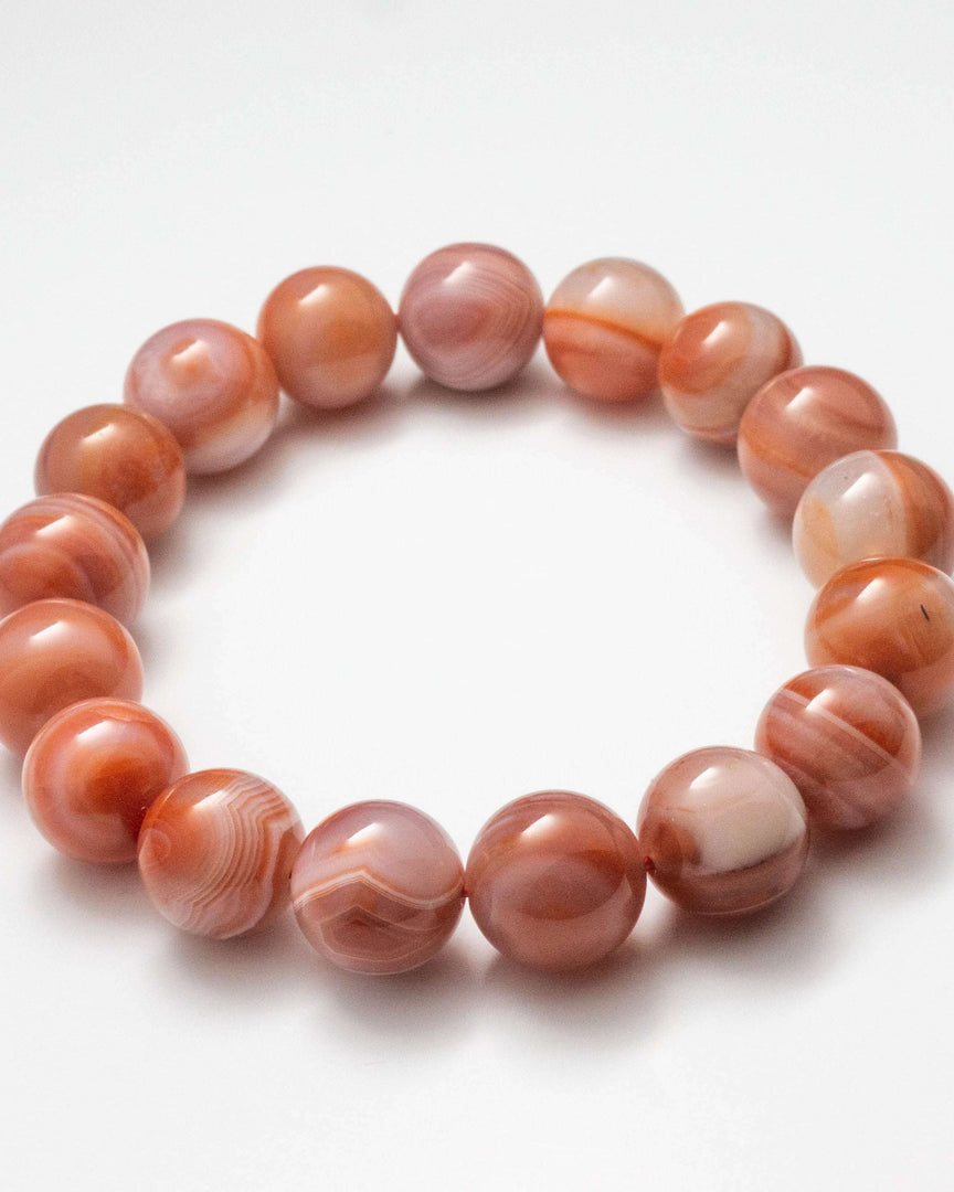 Beaded bracelet with pink and orange marbled beads on a white background