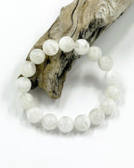 Load image into Gallery viewer, White beaded bracelet on a piece of driftwood against a white background