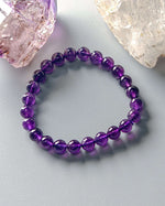 Load image into Gallery viewer, Purple beaded bracelet on a light gray surface with crystal rocks.