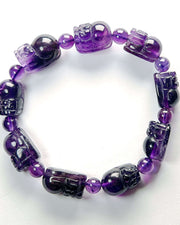 Purple beaded bracelet with skull designs on a white background