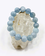 Load image into Gallery viewer, Blue beaded bracelet on a crystal rock with a white background
