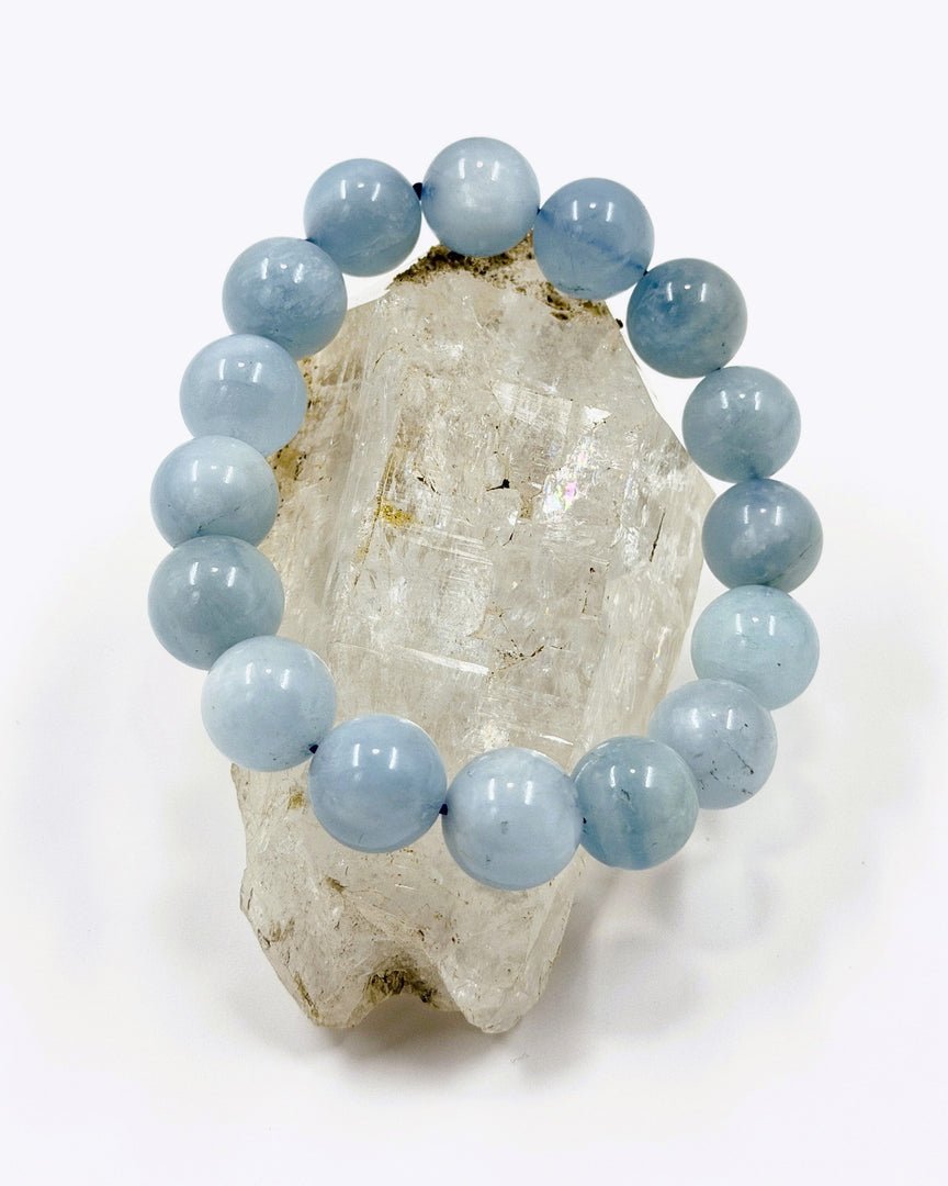 Blue beaded bracelet on a crystal rock with a white background