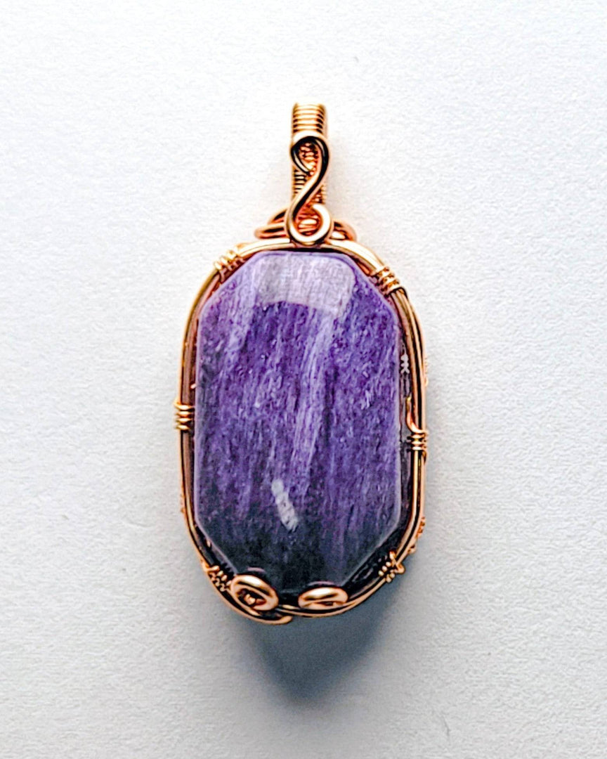 Purple stone pendant with gold wire wrapping on a white background