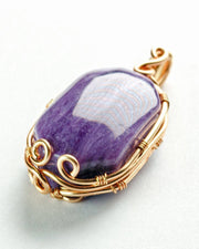 Purple stone pendant with gold wire wrapping on a white background