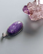 Load image into Gallery viewer, Purple pendant with silver setting on a gray background
