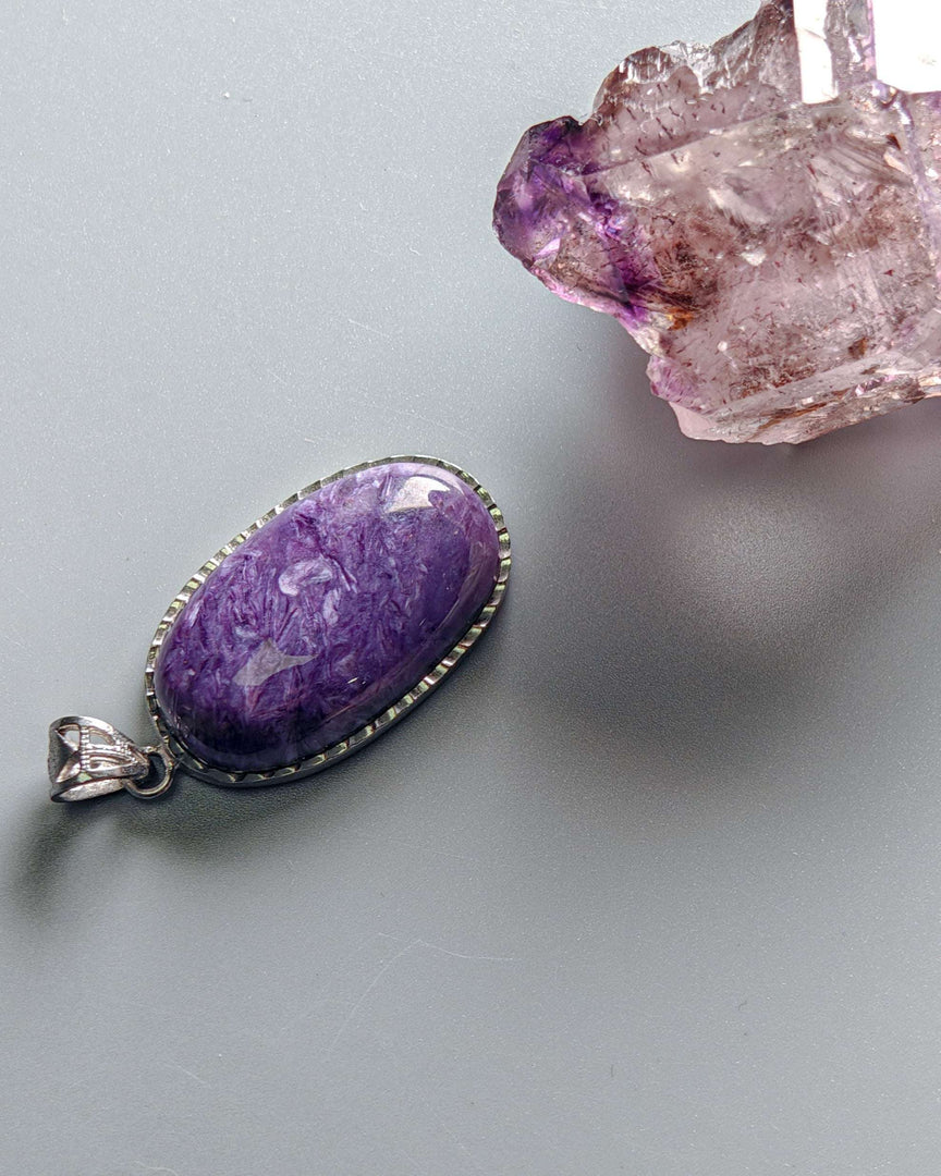 Purple pendant with silver setting on a gray background