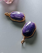 Load image into Gallery viewer, Two purple stone pendants with gold wire wrapping on a gray surface
