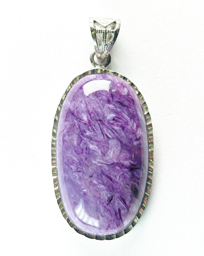 Purple stone pendant with silver frame on a white background