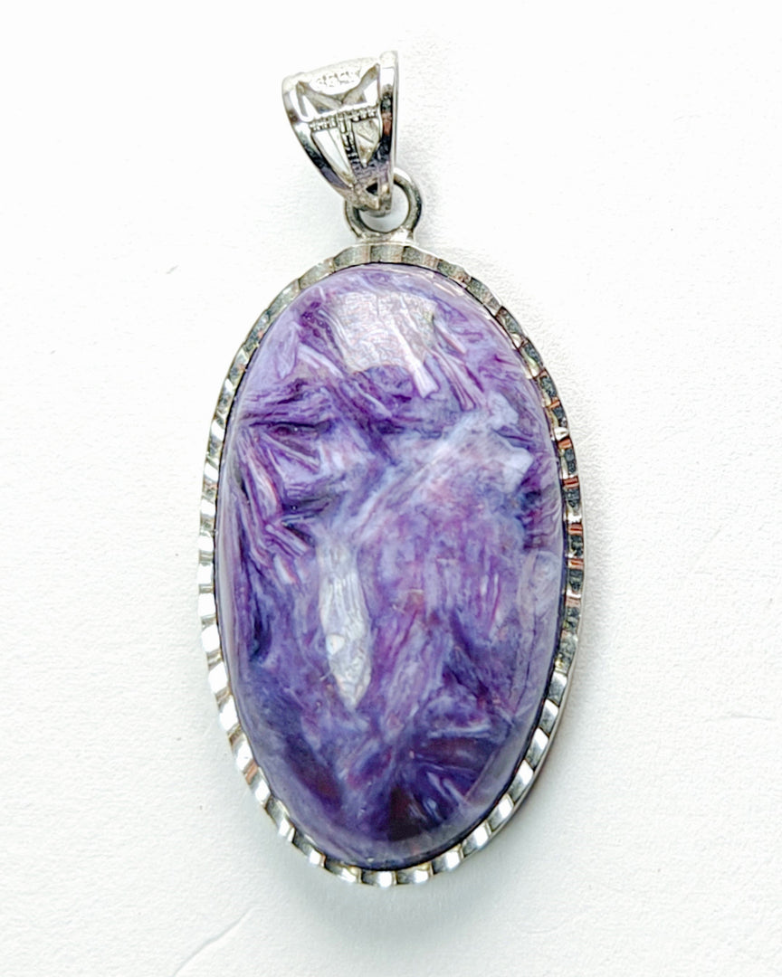 Purple stone pendant with silver frame on white background