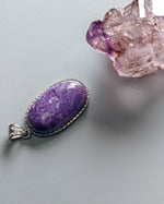 Load image into Gallery viewer, Purple pendant with silver setting on a gray background
