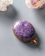Load image into Gallery viewer, Purple stone pendant with gold wire wrapping on a gray surface
