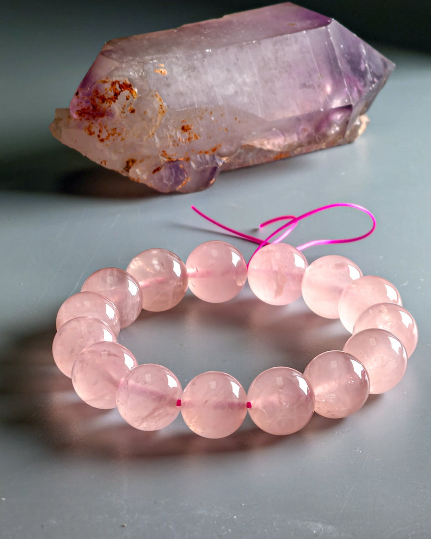 Pink beaded bracelet with a pink crystal on a gray surface