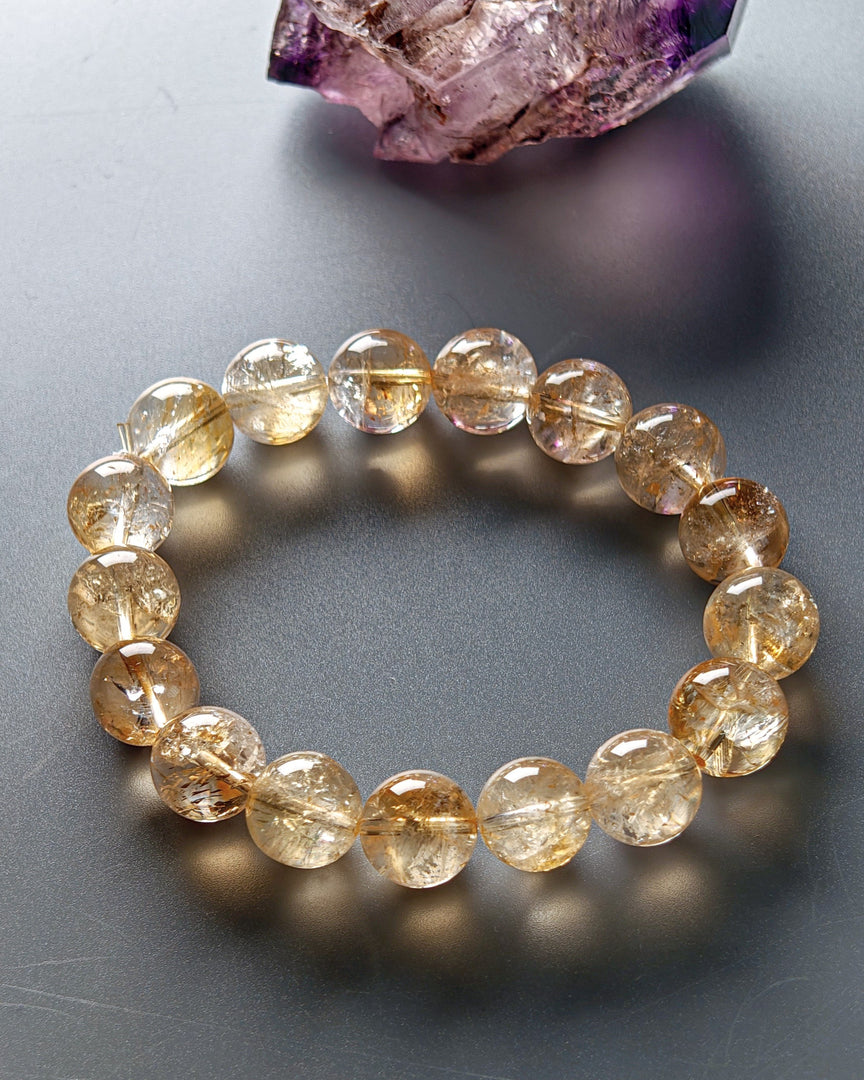 Beaded bracelet with yellow gemstones on a gray surface with crystals in the background