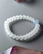 Load image into Gallery viewer, Beaded bracelet with a single blue bead on a gray surface

