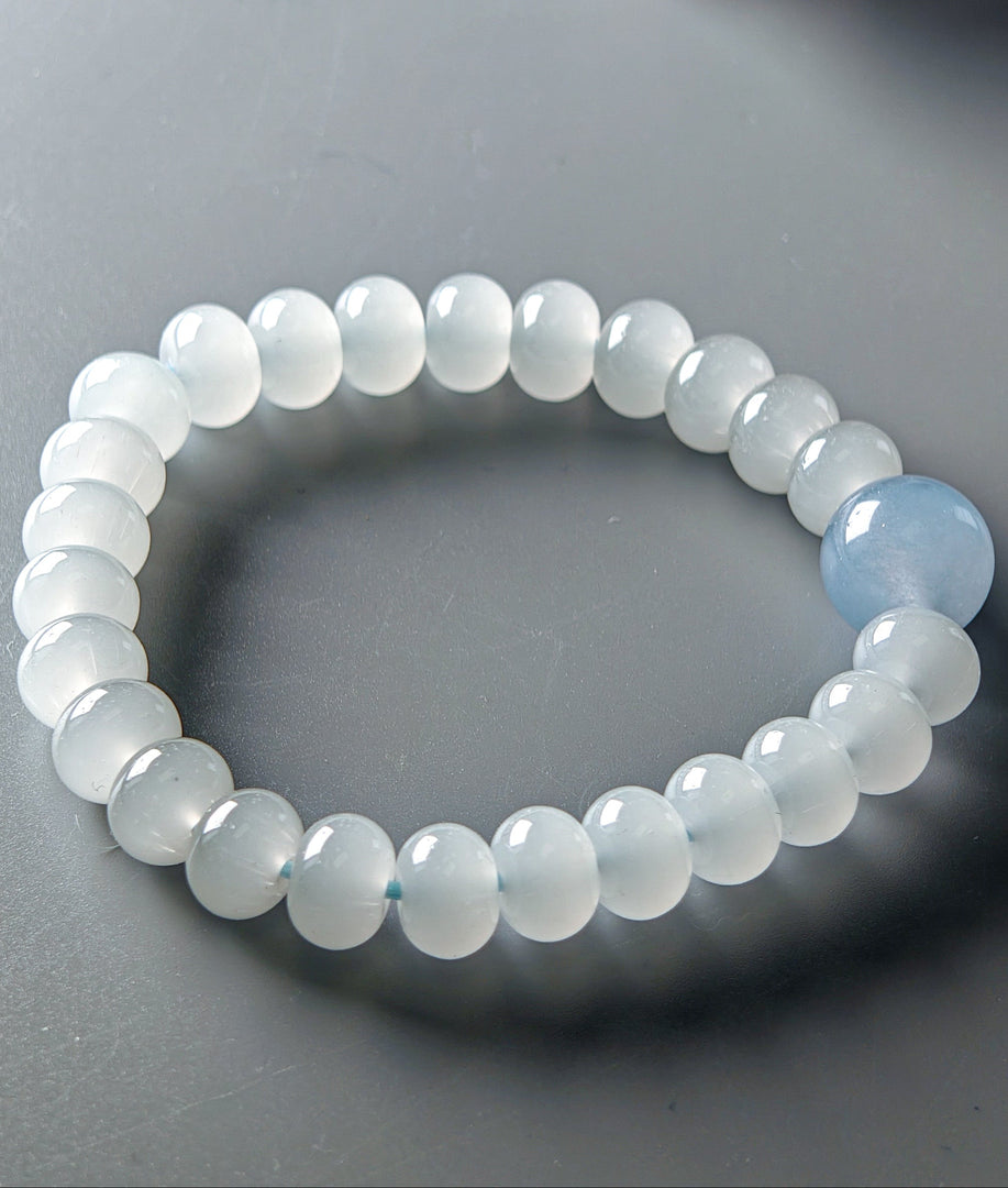 Beaded bracelet with a single blue bead on a gray background