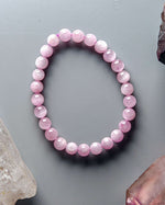 Load image into Gallery viewer, Pink beaded bracelet on a gray surface with crystals around
