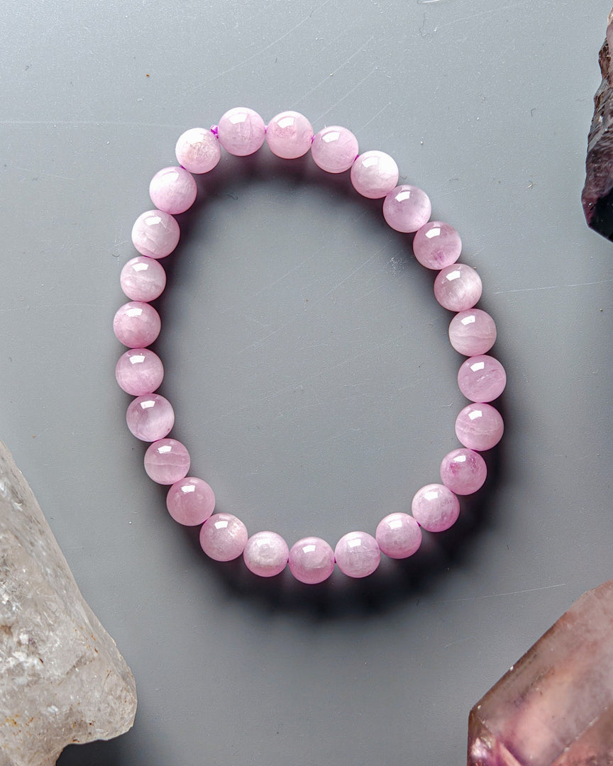 Pink beaded bracelet on a gray surface with crystals around