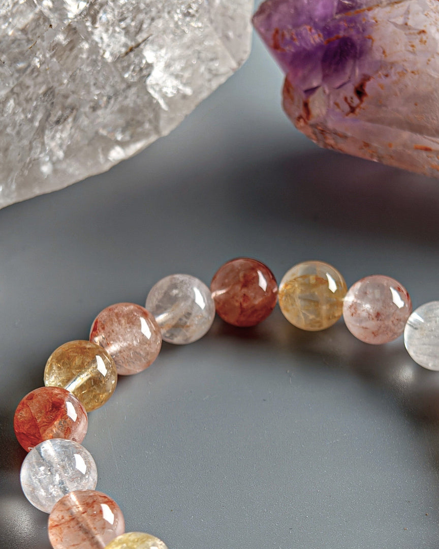 Multicolored gemstone bracelet on a dark surface with a crystal in the background