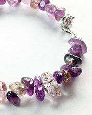 Close-up of a bracelet with purple and pink gemstones on a white background