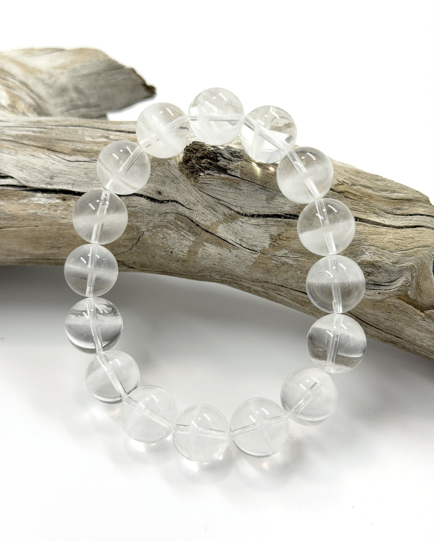 Clear beaded bracelet on a wooden branch with a white background