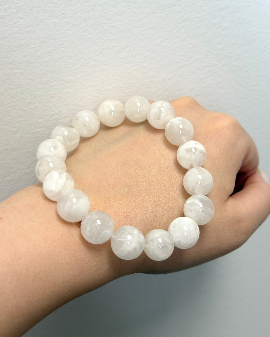 White beaded bracelet on a wrist against a plain background