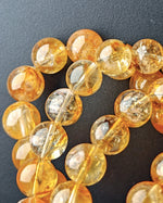 Load image into Gallery viewer, Close-up of amber-colored beads on a dark background

