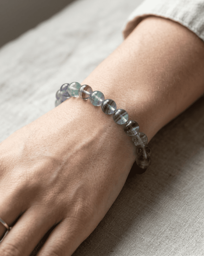 Close-up of a wrist wearing a beaded bracelet on a neutral background