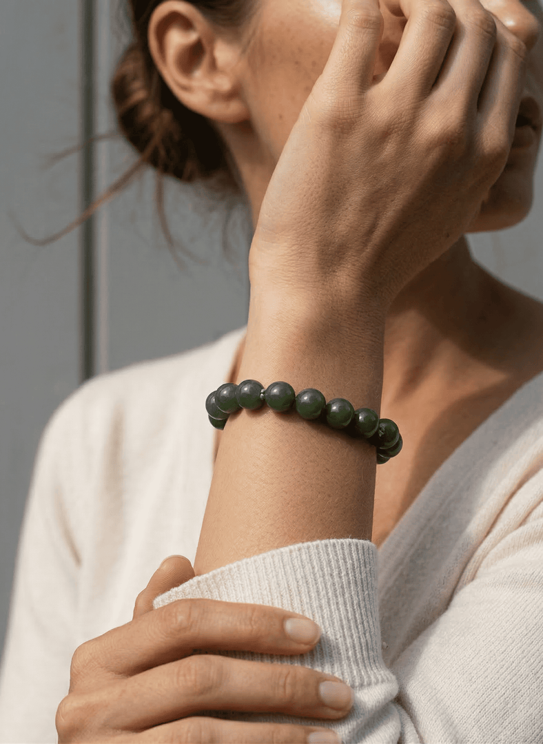 Person wearing a green beaded bracelet on a neutral background