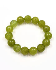 A beaded stretch bracelet made of smooth, polished round beads in a translucent olive green color, displayed on a clean white background.