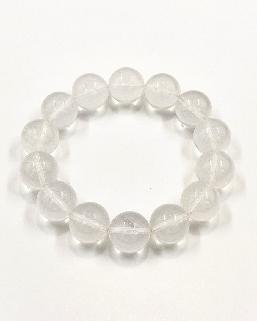 A beaded stretch bracelet made of clear, polished oval gemstone beads, arranged in a circle on a plain white background.