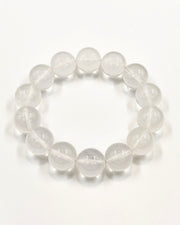 A beaded stretch bracelet made of clear, polished oval gemstone beads, arranged in a circle on a plain white background.