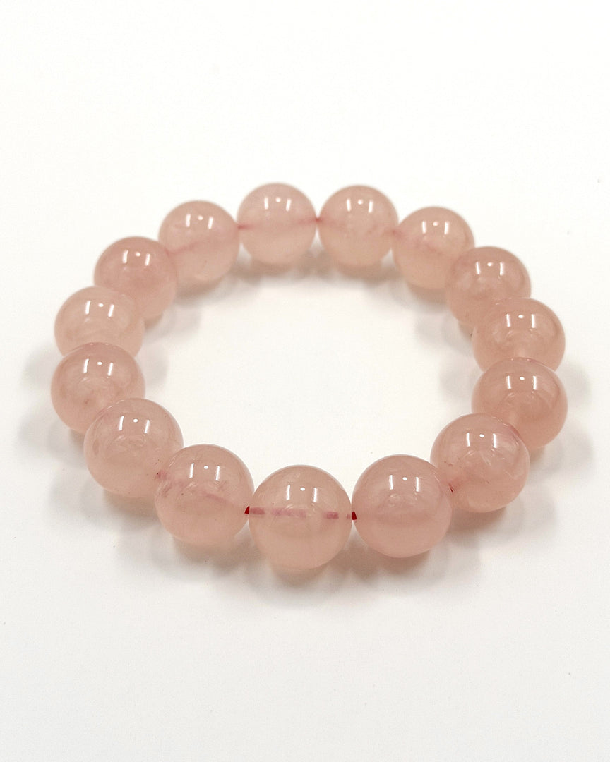 A beaded stretch bracelet made of smooth, translucent light pink round beads, displayed on a clean white background.