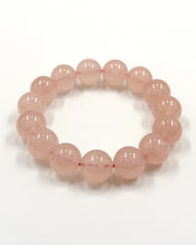 A beaded stretch bracelet made of smooth, translucent light pink round beads, displayed on a clean white background.