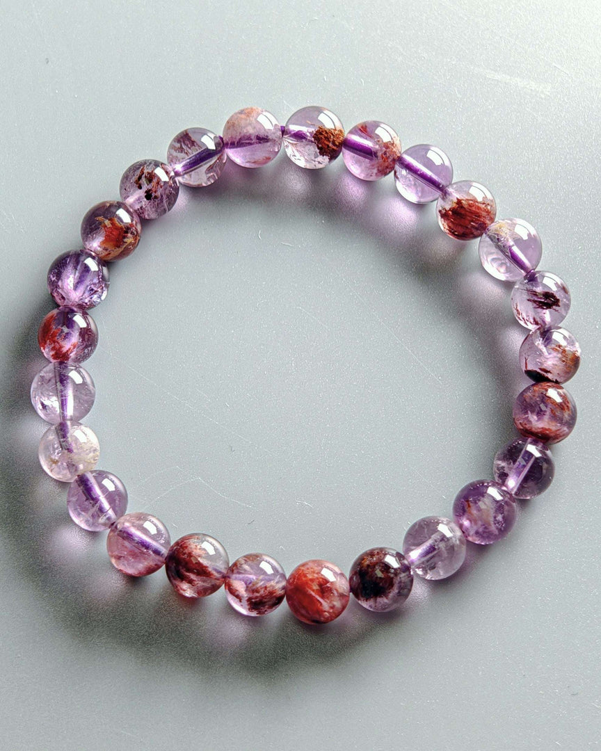 Beaded bracelet with pink and purple stones on a light gray background