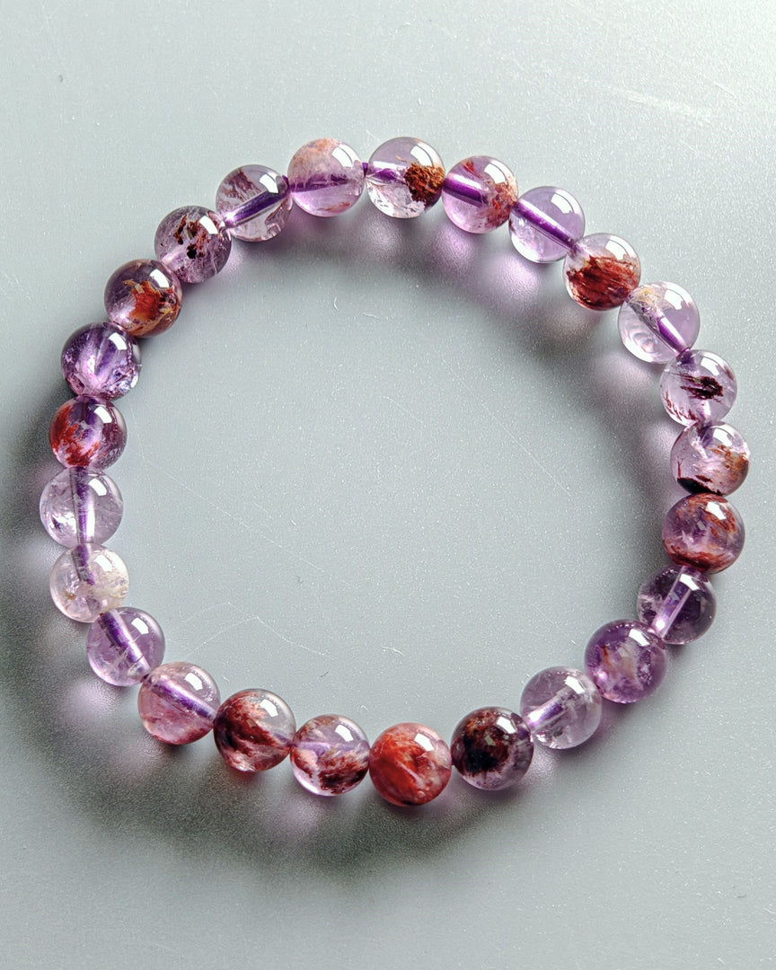 Beaded bracelet with pink and purple stones on a light gray background