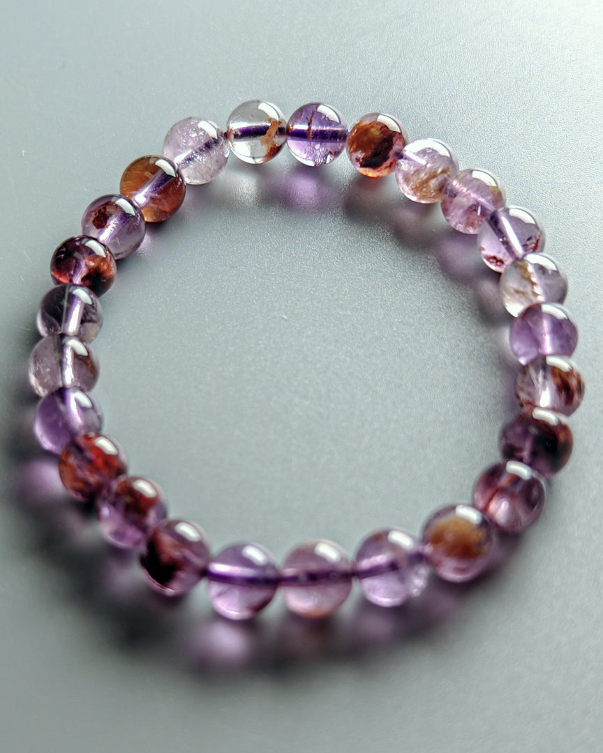 Beaded bracelet with purple and brown beads on a light gray background